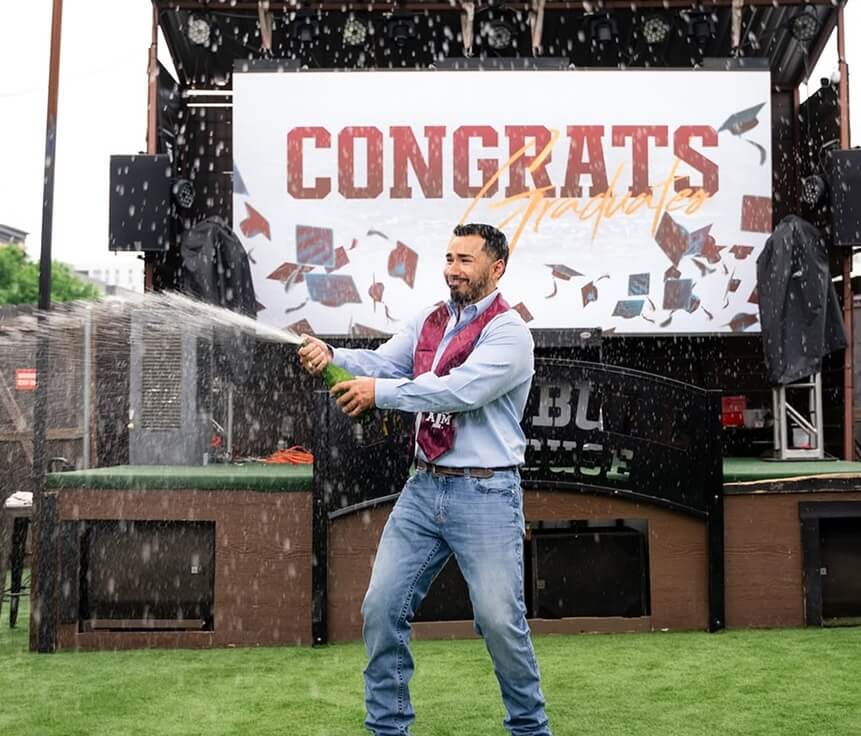 Man celebrating graduates with champaign